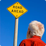 A older man looks at a sign which reads "Road Ahead".