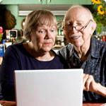An older man and woman search for information on the internet.